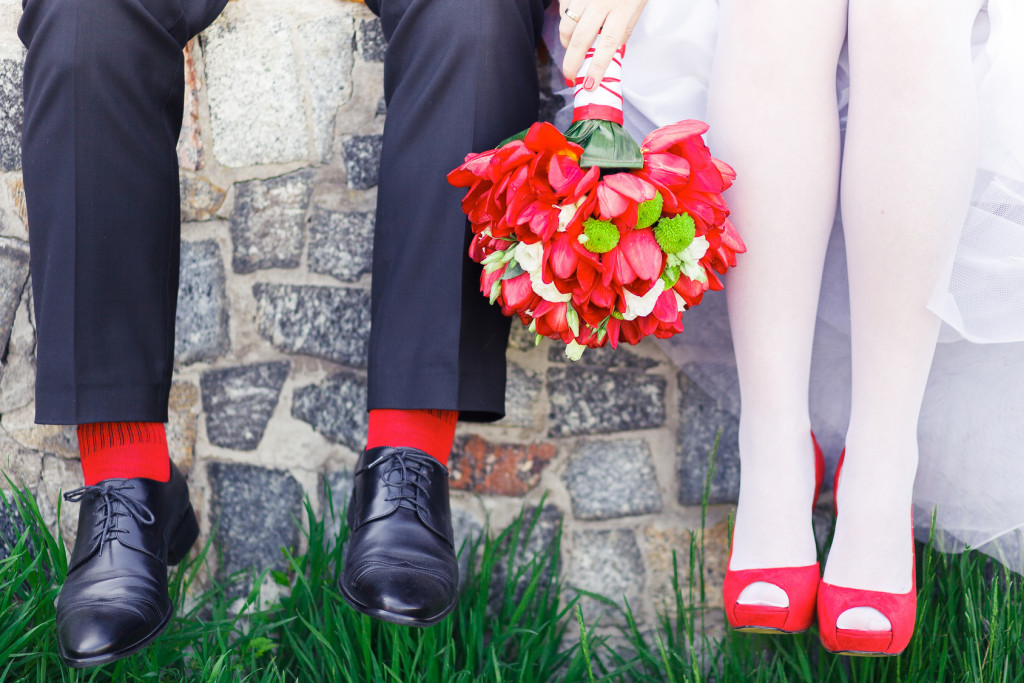 bride and groom with red shoes and socks and a bouqet of red flowers